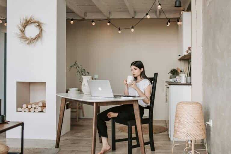 Vrouw werkt ontspannen aan een bureau in een minimalistisch en opgeruimd huis.