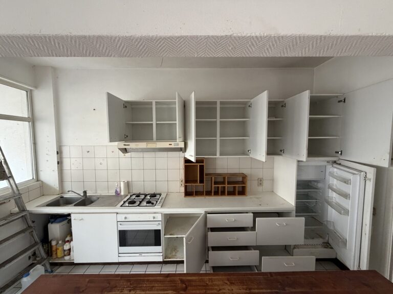 Dezelfde keuken leeg, kasten open, na de ontruiming